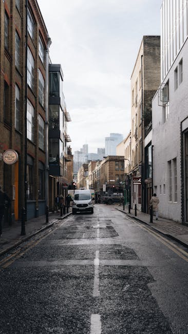 A street scene on Choumert Road in Peckham showing a gradual incline with residential buildings and trees lining the pavement. In the foreground, a silver Audi falls within a parking lane on the right
